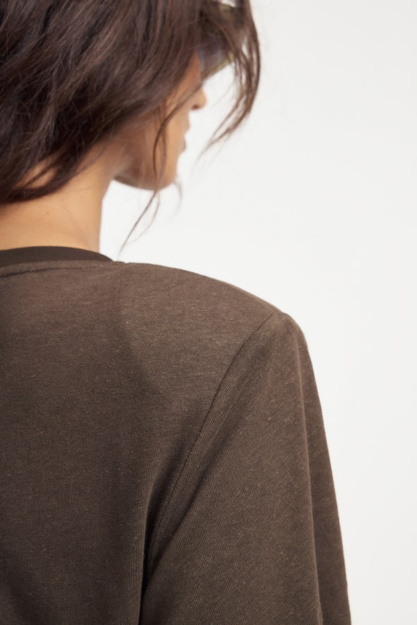 Brown linen tee bodysuit worn by a woman on a grey background