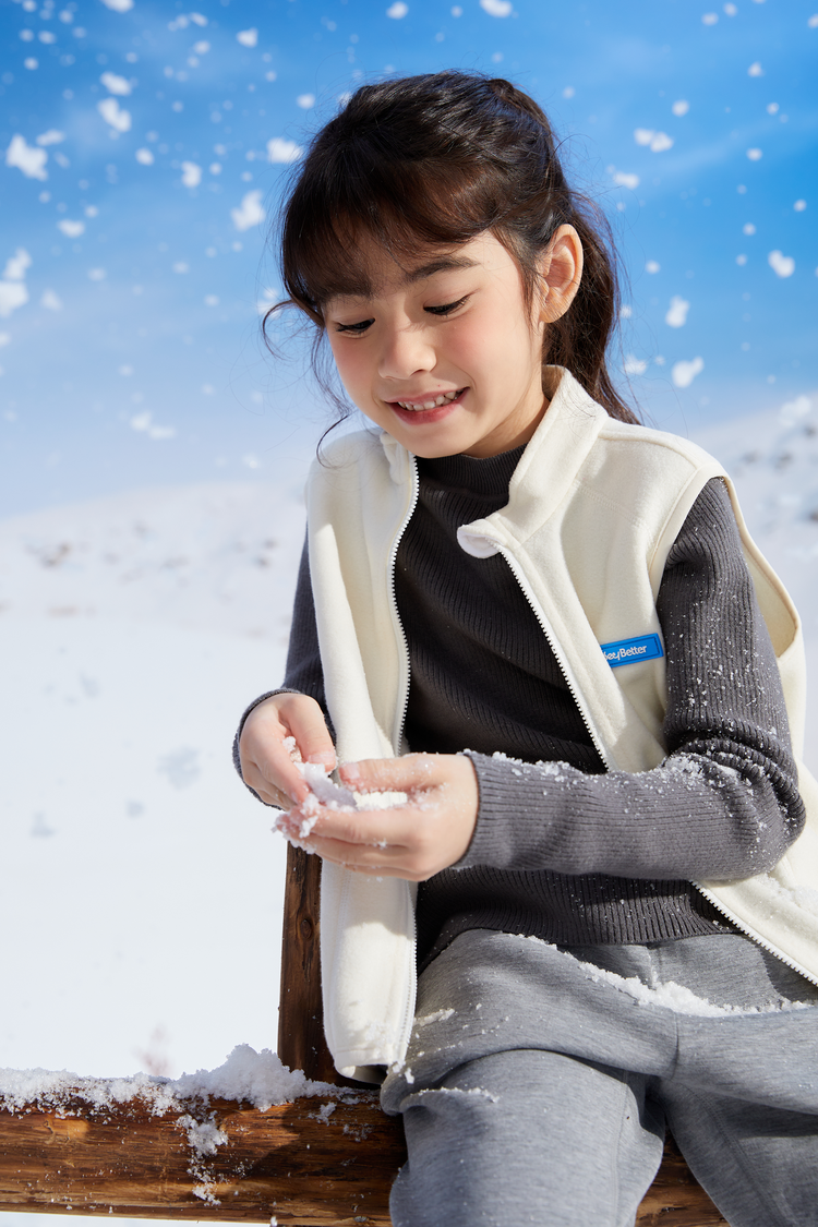 A girl wearing a pink soft lightweight vest with a logo in a snowy landscape