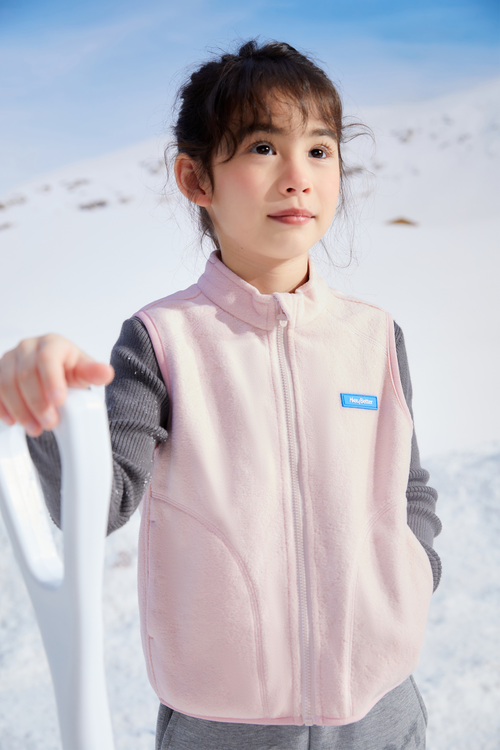 A girl wearing a pink soft lightweight vest with a logo in a snowy landscape