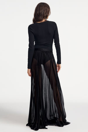 Woman wearing a black long-sleeve Henley bodysuit on a white background