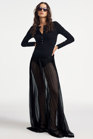 Woman wearing a black long-sleeve Henley bodysuit on a white background