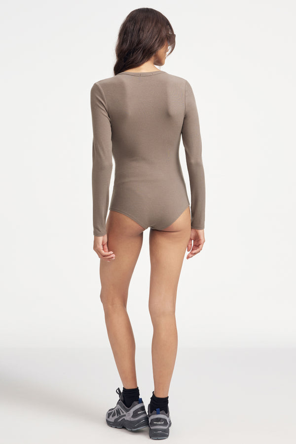 Woman wearing a brown long-sleeve button-up Henley bodysuit